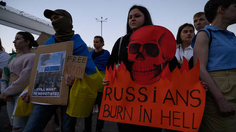 FILE PHOTO: A demonstrator is holding a placard depicting a skull that reads 'Russians burn in hell' in Warsaw, Poland.